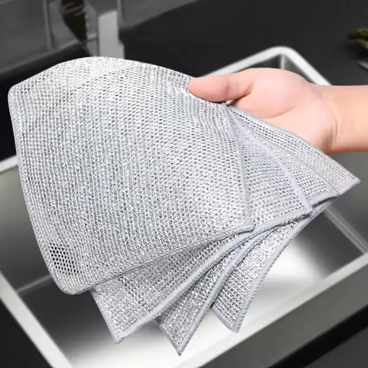 Person holding a textured cleaning dishcloth over a sink