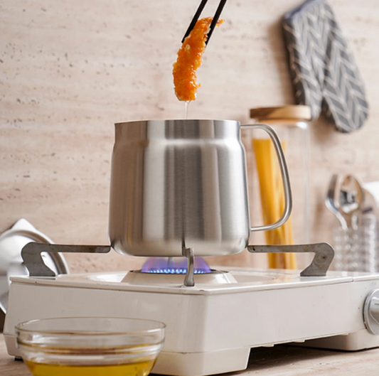 Stir-frying food over a portable stove with a metal pot.
