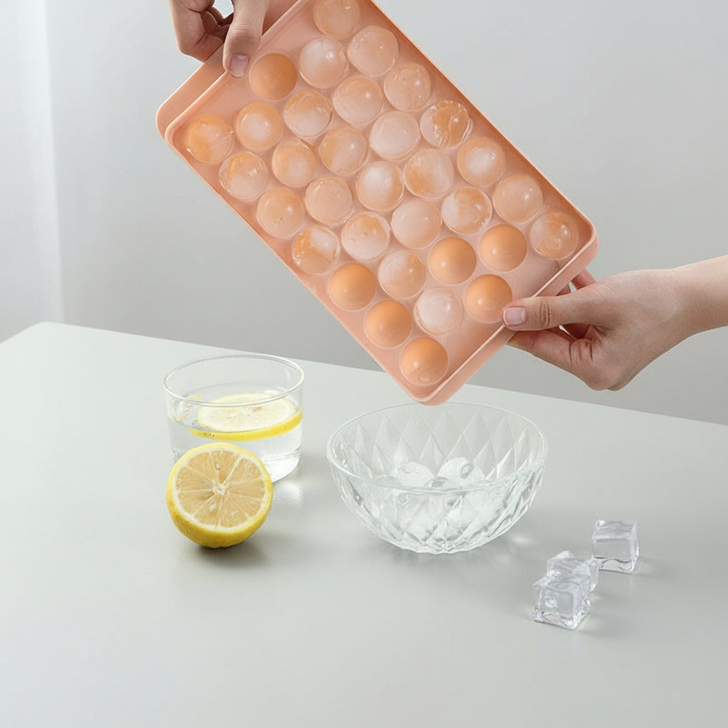 Pink silicone ice cube tray with round compartments, held by hands on a light gray background.