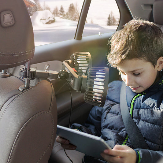 Child sitting in a car using a backseat fan and  tablet.