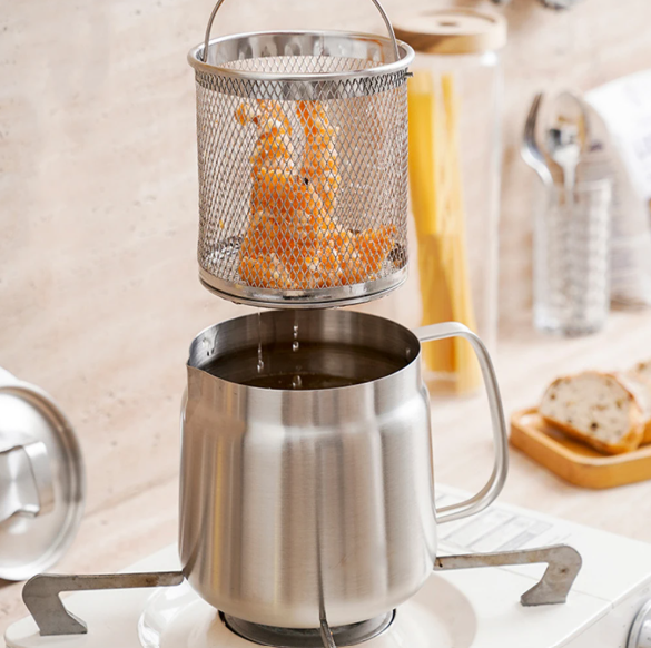 Stainless steel oil pot strainer with mesh basket on a kitchen counter